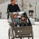 father cycling with sons in trailer
