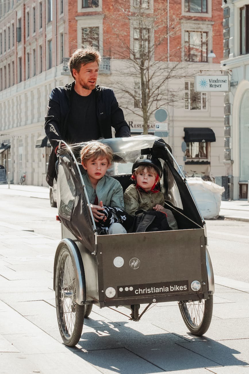 father cycling with sons in trailer
